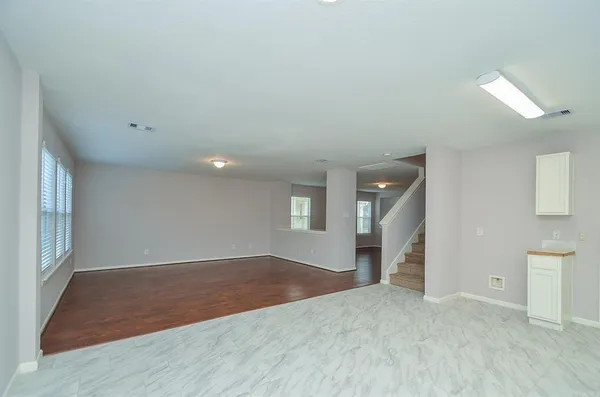 an empty room with wooden floor and windows