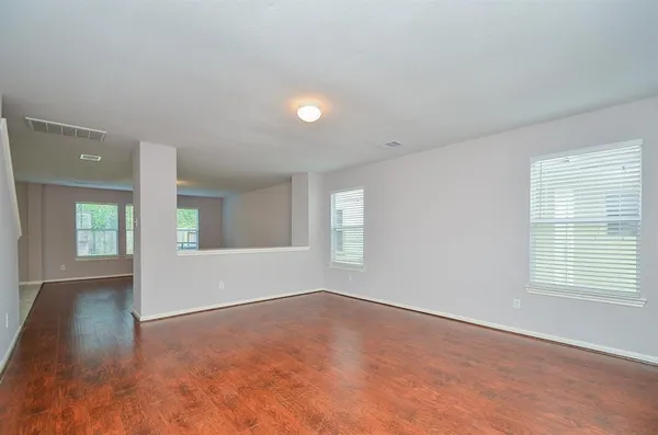 a view of an empty room with wooden floor and a window