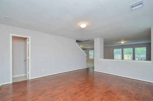 an empty room with wooden floor and windows