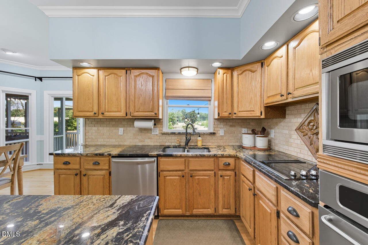8713 Mourning Dove Road Raleigh, NC 27615 - Photo 15 of 56 a kitchen with kitchen island granite countertop a sink appliances cabinets and a counter top space
