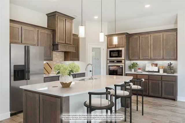 a kitchen with stainless steel appliances a dining table chairs refrigerator and microwave