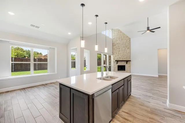 a open kitchen with kitchen island a sink dishwasher stove and oven with wooden floor