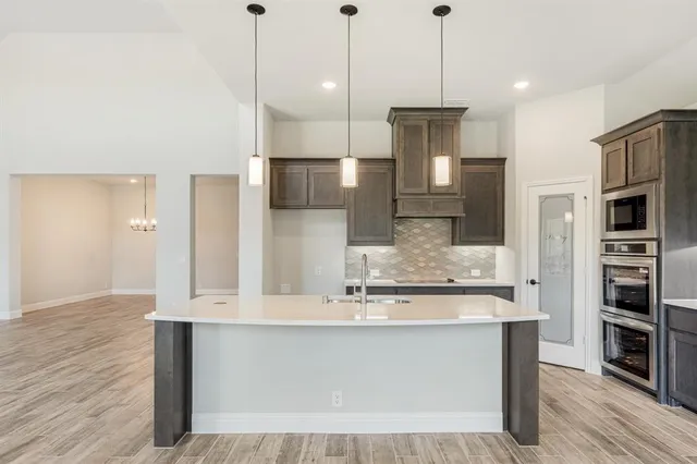 a kitchen with kitchen island a counter top space stainless steel appliances and wooden floor