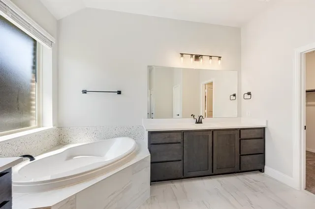 a bathroom with a tub sink and mirror