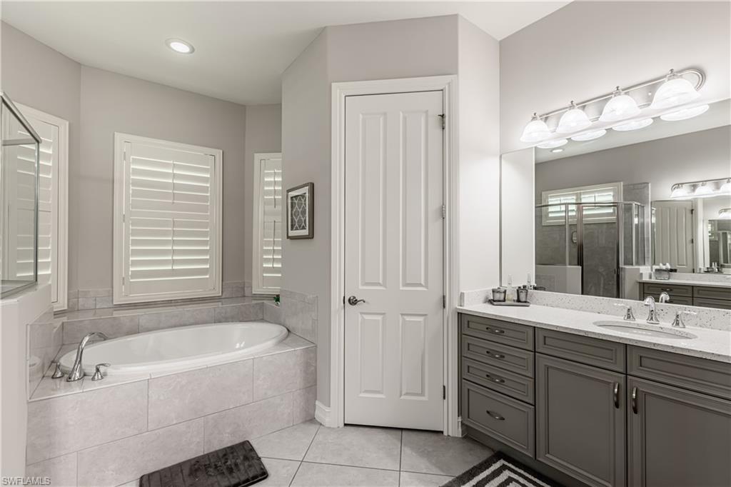 7307 Acorn Way Naples, FL 34119 - Photo 11 of 22 Full bath featuring vanity, a shower stall, light tile patterned flooring, and a bath