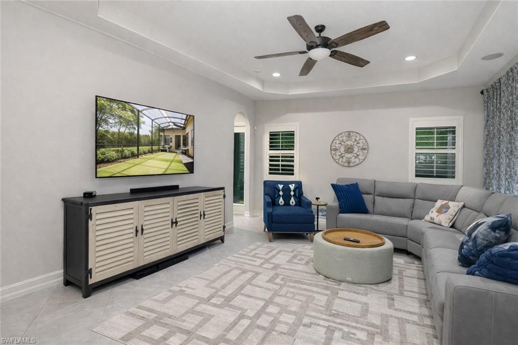 7307 Acorn Way Naples, FL 34119 - Photo 3 of 22 Living room featuring a tray ceiling, arched walkways, ceiling fan, and recessed lighting