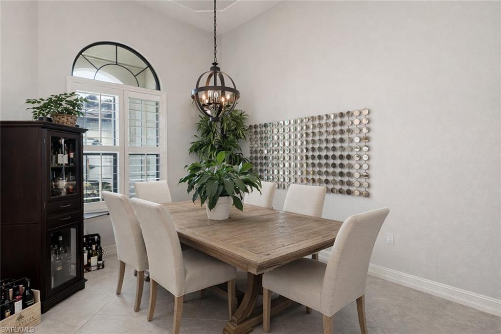 7307 Acorn Way Naples, FL 34119 - Photo 7 of 22 Dining area featuring a chandelier, light tile patterned floors, and a high ceiling