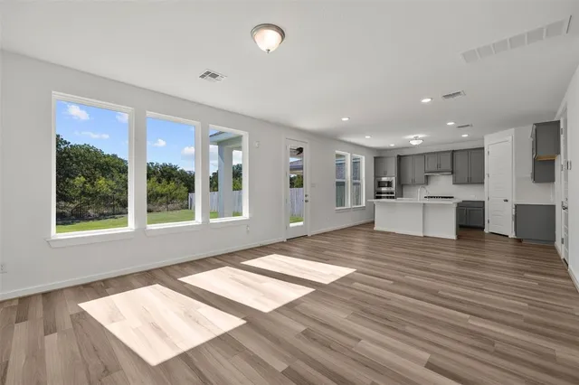 a view of an empty room with kitchen view and a window