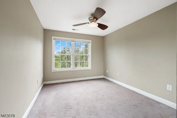 an empty room with a ceiling fan and windows