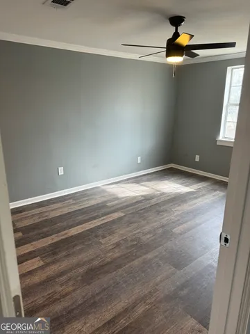 a view of an empty room with window and wooden floor