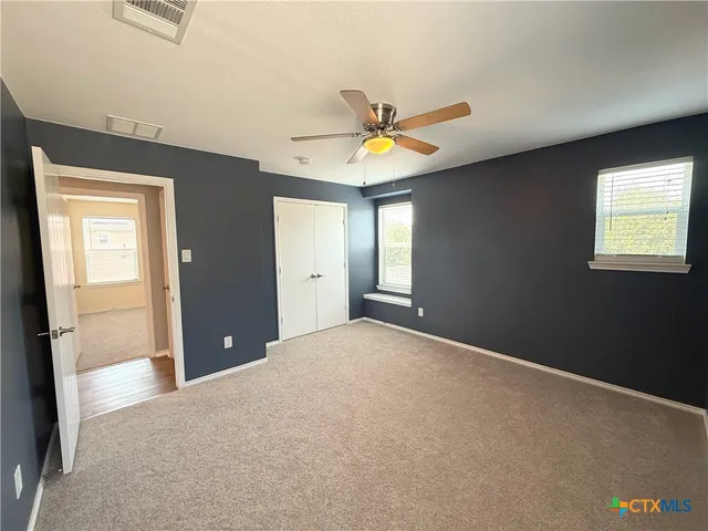 an empty room with a window and a ceiling fan