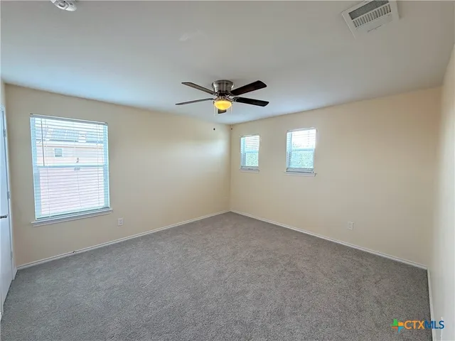 an empty room with windows and ceiling fan