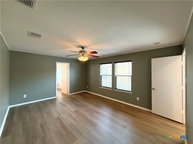 an empty room with wooden floor and windows