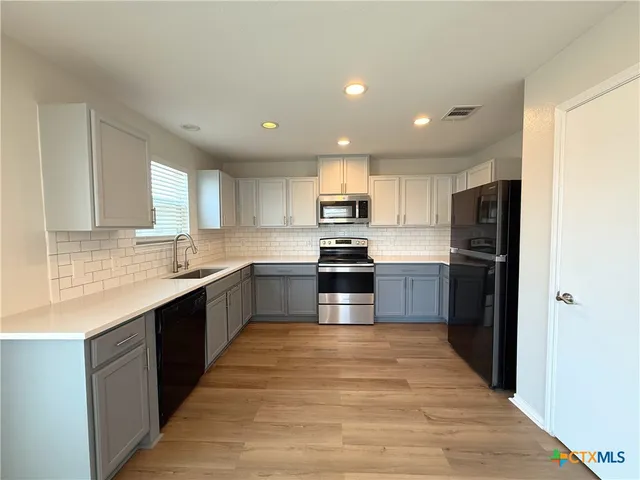 a large kitchen with stainless steel appliances granite countertop a refrigerator and a sink