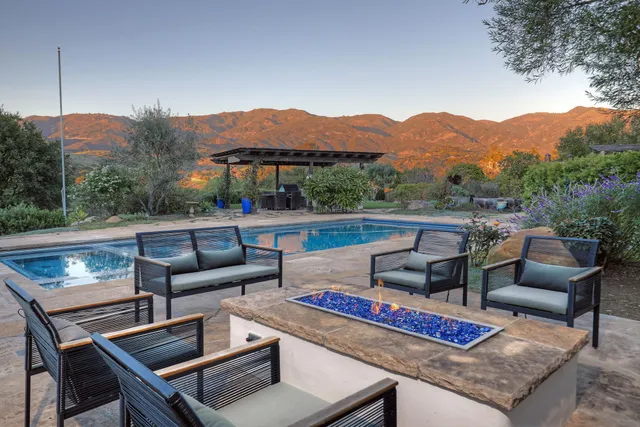 a view of a patio with couches chairs and a table and chairs with wooden fence