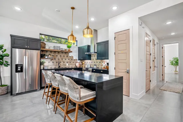a kitchen with stainless steel appliances kitchen island granite countertop a refrigerator and a sink