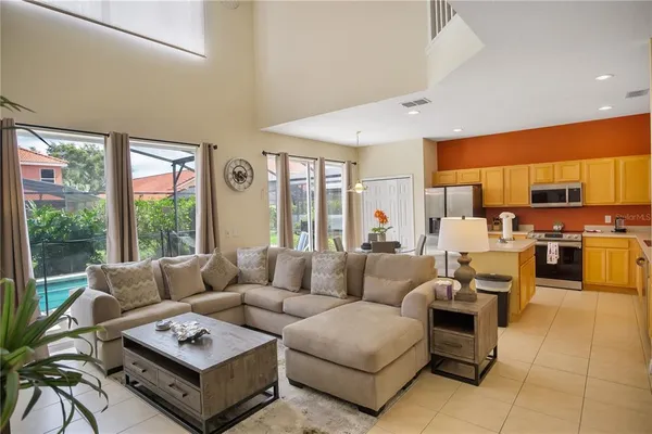 a living room with furniture potted plant kitchen view and a large window