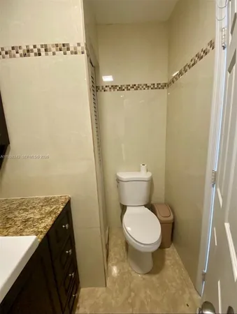 a bathroom with a granite countertop toilet and a sink