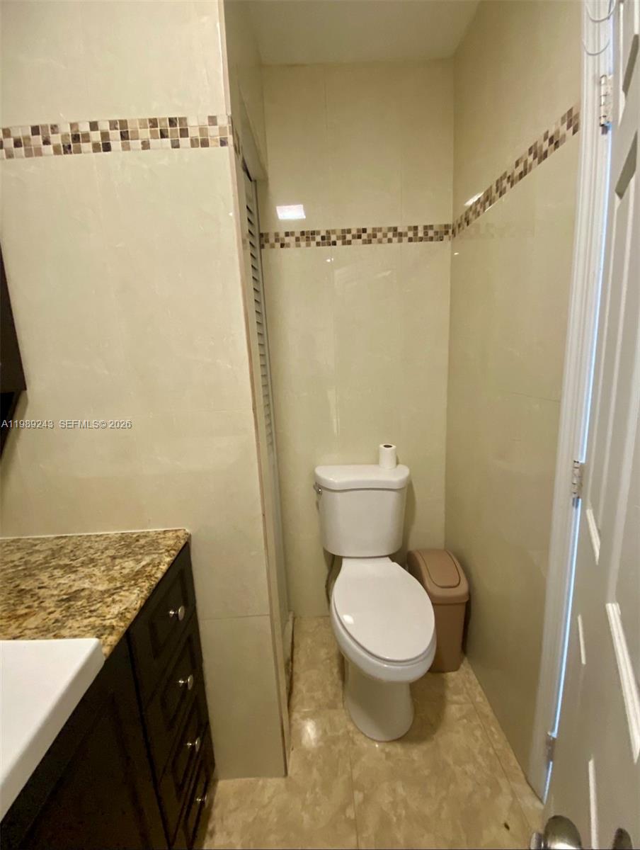 14855 Southwest 174th Street, Unit 1 Miami, FL 33187 - Photo 3 of 5 a bathroom with a granite countertop toilet and a sink