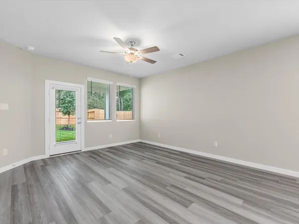 a view of an empty room with a window and wooden floor