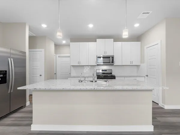 a kitchen with stainless steel appliances granite countertop a sink a refrigerator and white cabinets