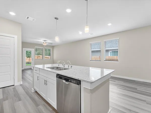 a hall with kitchen island a stove a wooden floor and a sink