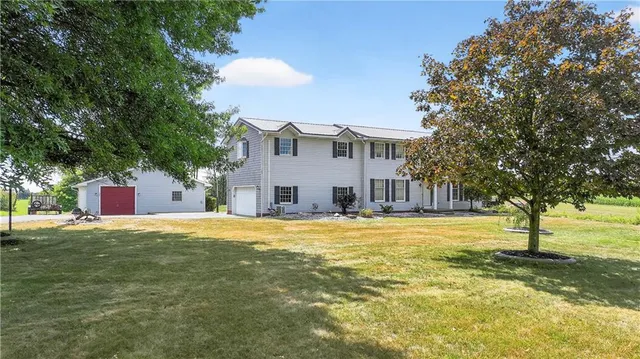 a view of a house with a yard and large tree