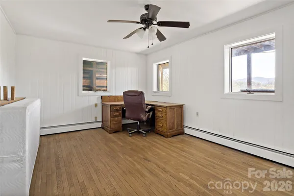 a view of empty room with wooden floor and fan