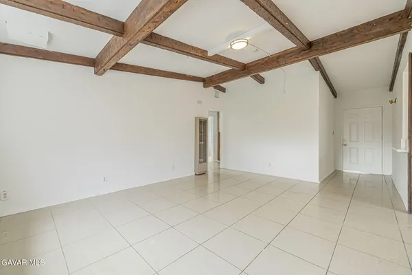 an empty room with a chandelier fan and windows