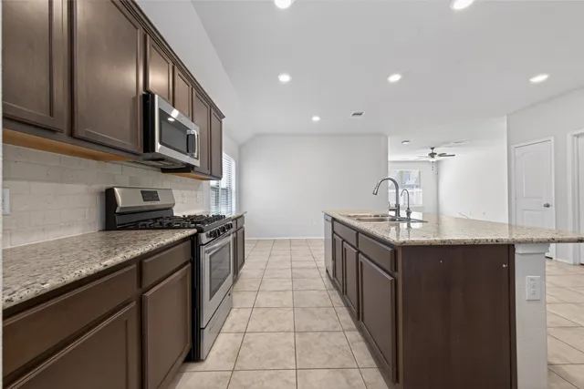 a kitchen with granite countertop a refrigerator and a stove top oven