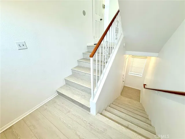 a view of staircase with wooden floor and white walls
