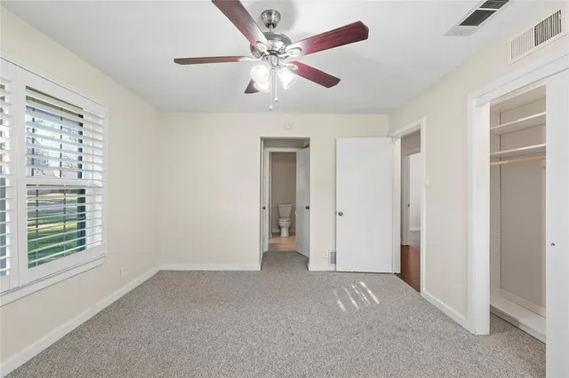 a view of empty room with window and ceiling fan