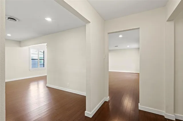 an empty room with wooden floor & windows