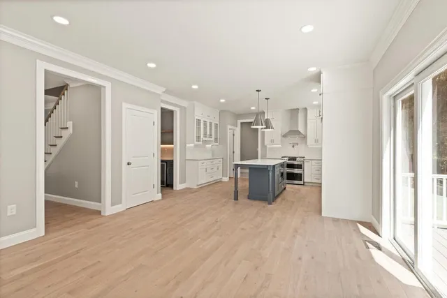 a view of kitchen with stainless steel appliances kitchen island refrigerator stove and wooden floor