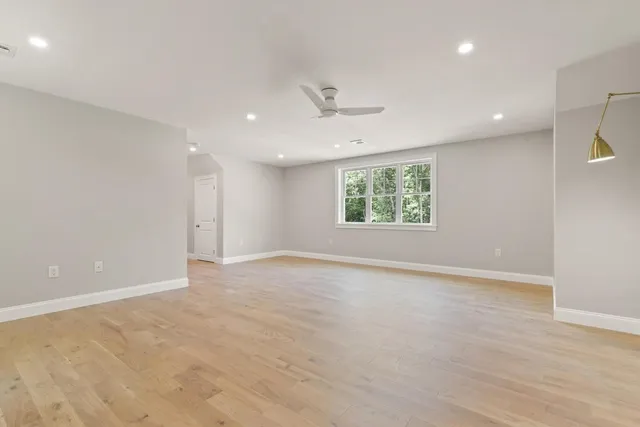 an empty room with wooden floor ceiling fan and windows