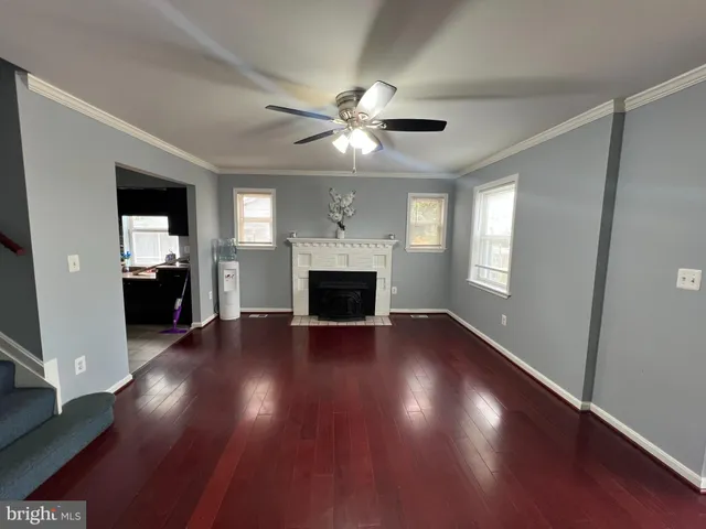 a view of an empty room with wooden floor and a ceiling fan