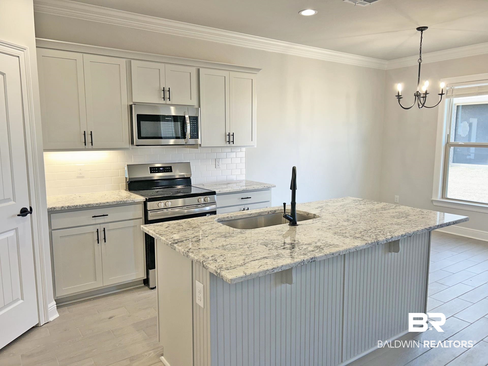 1748 Breckinridge Place Foley, AL 36535 - Photo 3 of 25 Kitchen with decorative backsplash, stainless steel appliances, light stone countertops, crown molding, and a breakfast bar