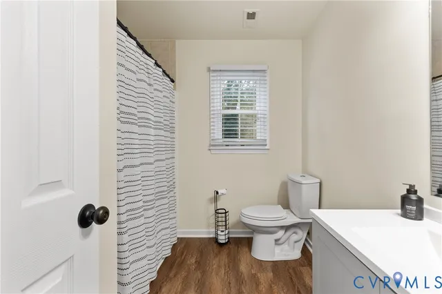 a bathroom with a sink and toilet with wooden floor
