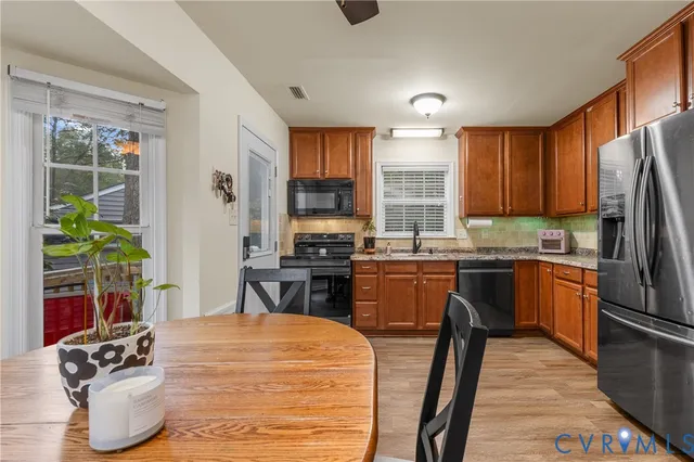 a kitchen with stainless steel appliances granite countertop a refrigerator a stove a sink dishwasher and wooden cabinets with wooden floor