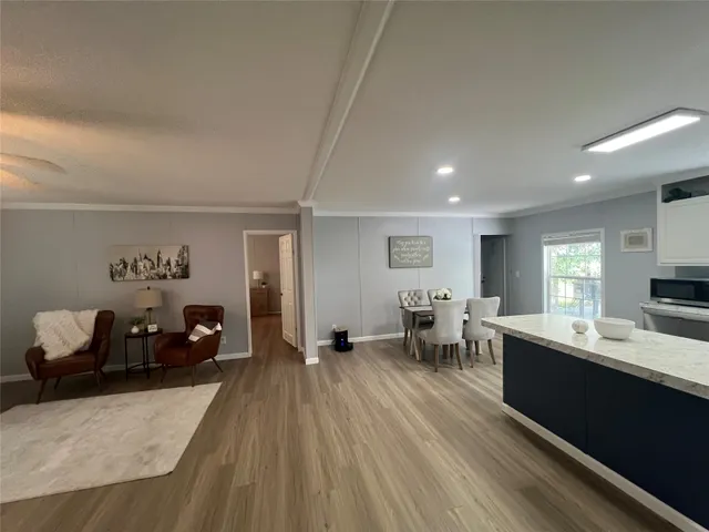 a large living room with stainless steel appliances kitchen island granite countertop furniture a rug and a window