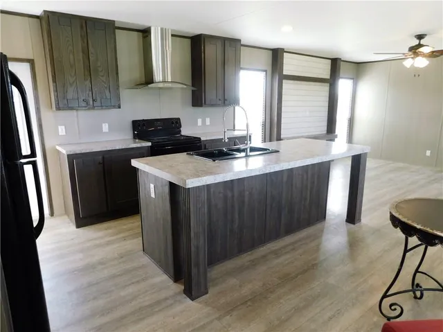 a kitchen with stainless steel appliances a refrigerator a sink dishwasher a stove and a dining table with wooden floor