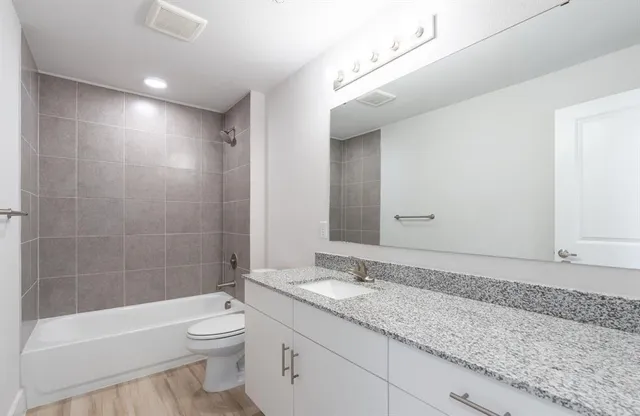 a bathroom with a granite countertop sink a toilet and shower