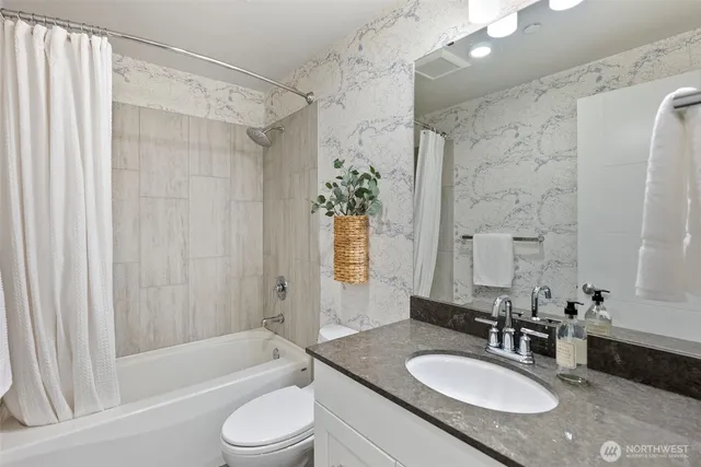 a bathroom with a granite countertop sink toilet bathtub and shower