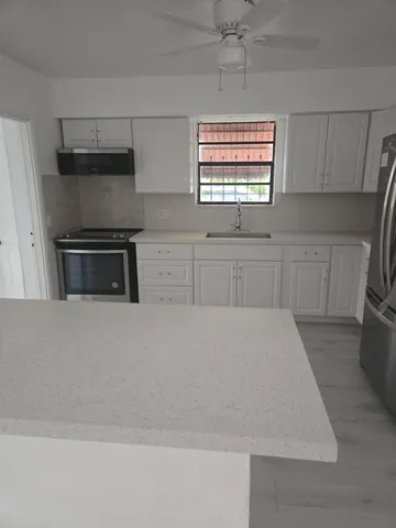 an empty room with wooden floor cabinet and windows