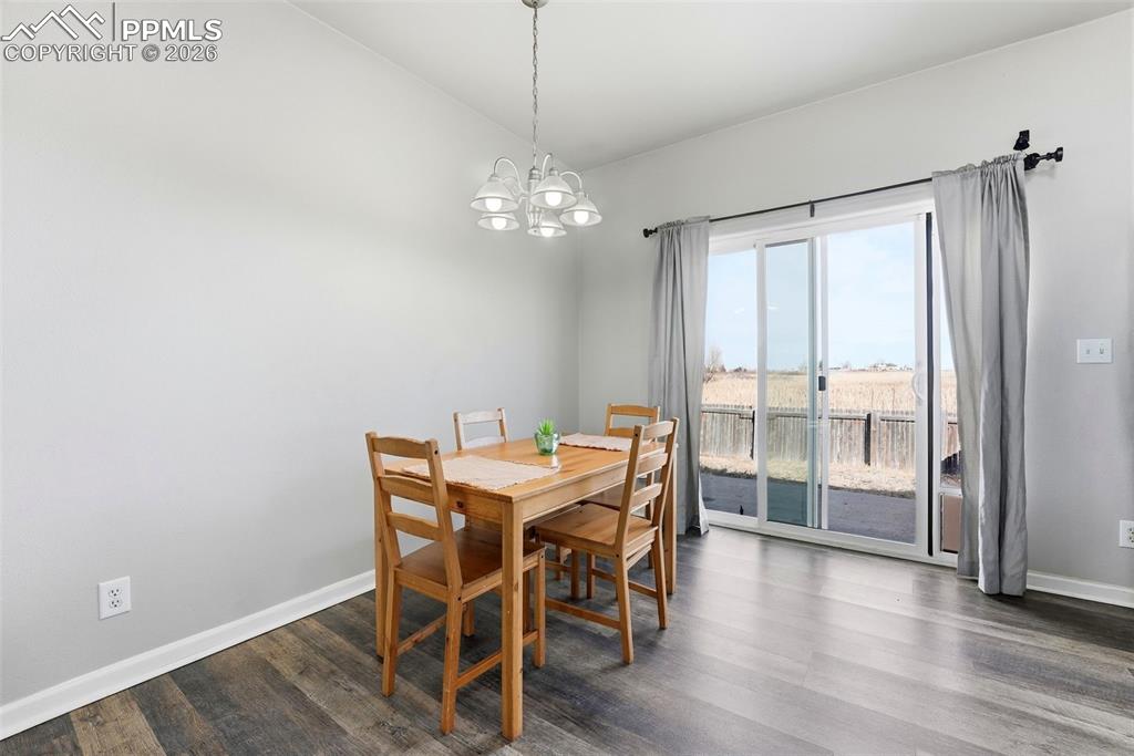 6535 Gelbvieh Road Peyton, CO 80831 - Photo 11 of 41 Dining room with vaulted ceiling, dark wood finished floors, and hanging lights