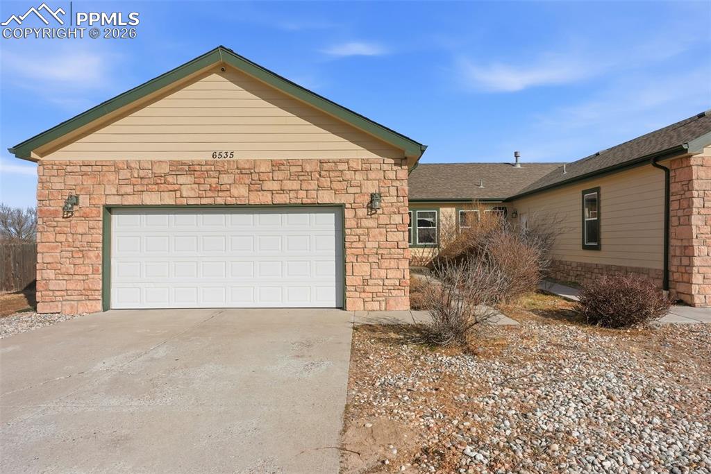 6535 Gelbvieh Road Peyton, CO 80831 - Photo 2 of 41 View of front of property with concrete driveway, an attached garage, and stone siding