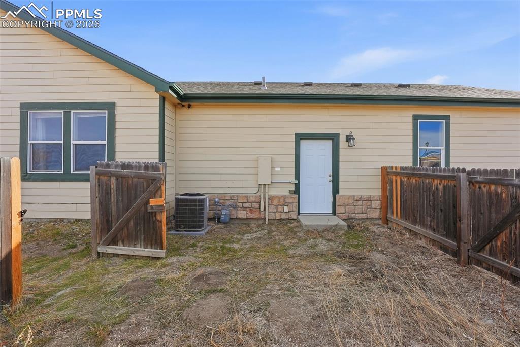 6535 Gelbvieh Road Peyton, CO 80831 - Photo 31 of 41 Back of property with a gate, stone siding, and a shingled roof