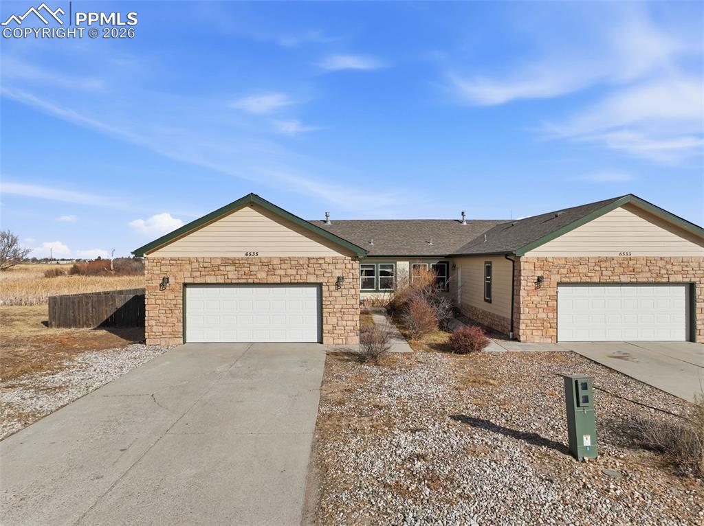 6535 Gelbvieh Road Peyton, CO 80831 - Photo 33 of 41 Single story home featuring stone siding, driveway, an attached garage, and a shingled roof