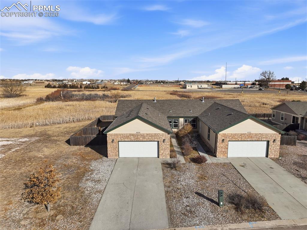 6535 Gelbvieh Road Peyton, CO 80831 - Photo 35 of 41 Ranch-style house with stone siding, an attached garage, and driveway