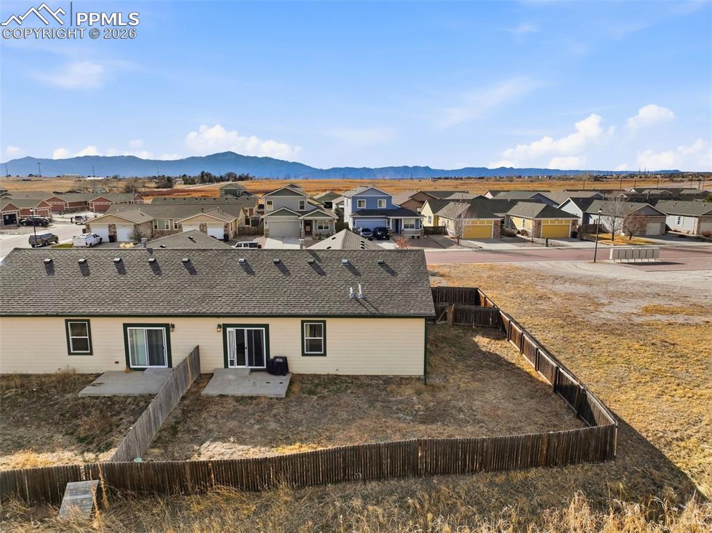 6535 Gelbvieh Road Peyton, CO 80831 - Photo 38 of 41 Rear view of property featuring a residential view, a mountain view, a fenced backyard, and a patio